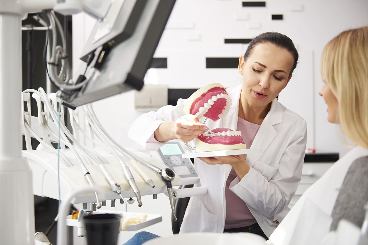 Provider using a large dental model to explain treatment options to a patient in the chair