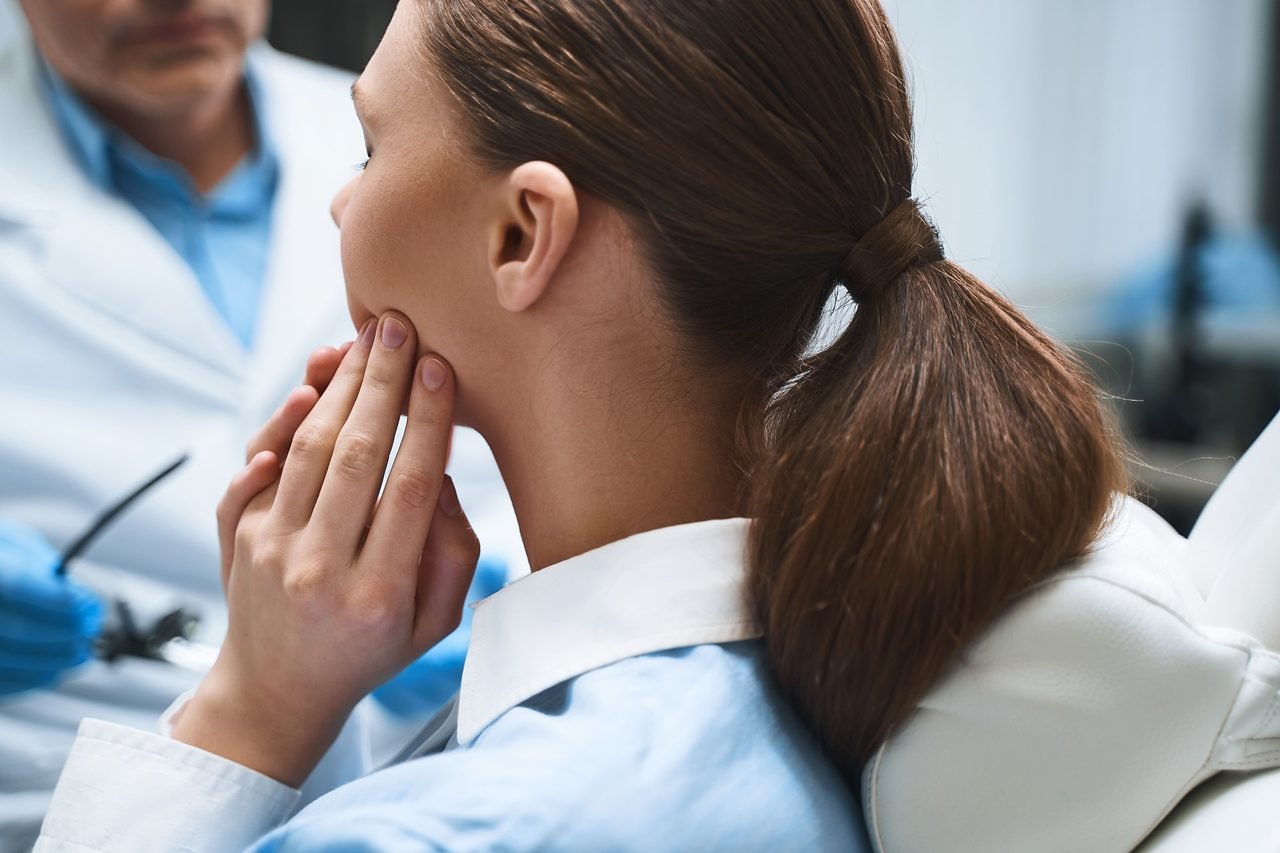 Patient pressing her fingers against her jaw while seated across from her provider