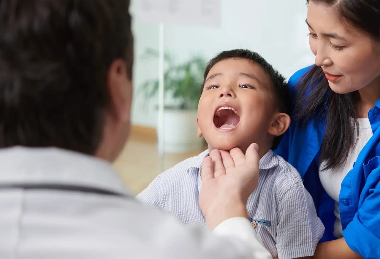 Pediatric specialist examining a young boy’s mouth and airway during a clinical evaluation for sleep apnea