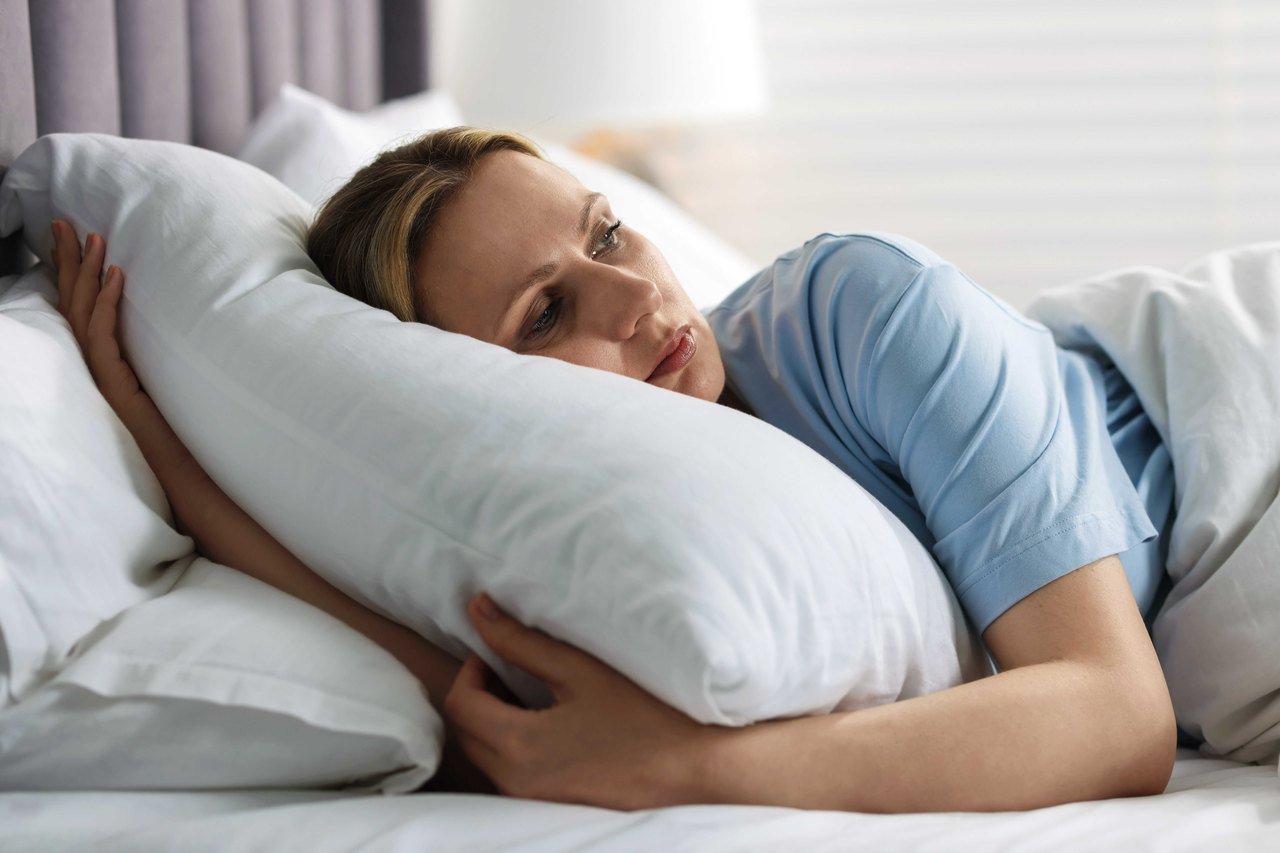 Unrefreshing sleep and the cognitive symptoms that follow Woman lying awake in bed looking tired after a night of broken sleep