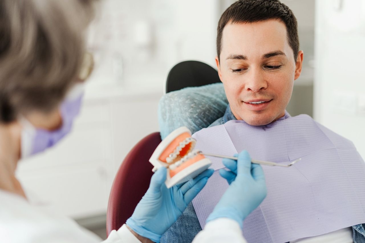 A screening comes before any treatment decision Provider using a dental model to talk through options with an adult patient